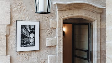 A stone wall with a framed black and white photo, a hanging light fixture, and a door leading to an interior space.