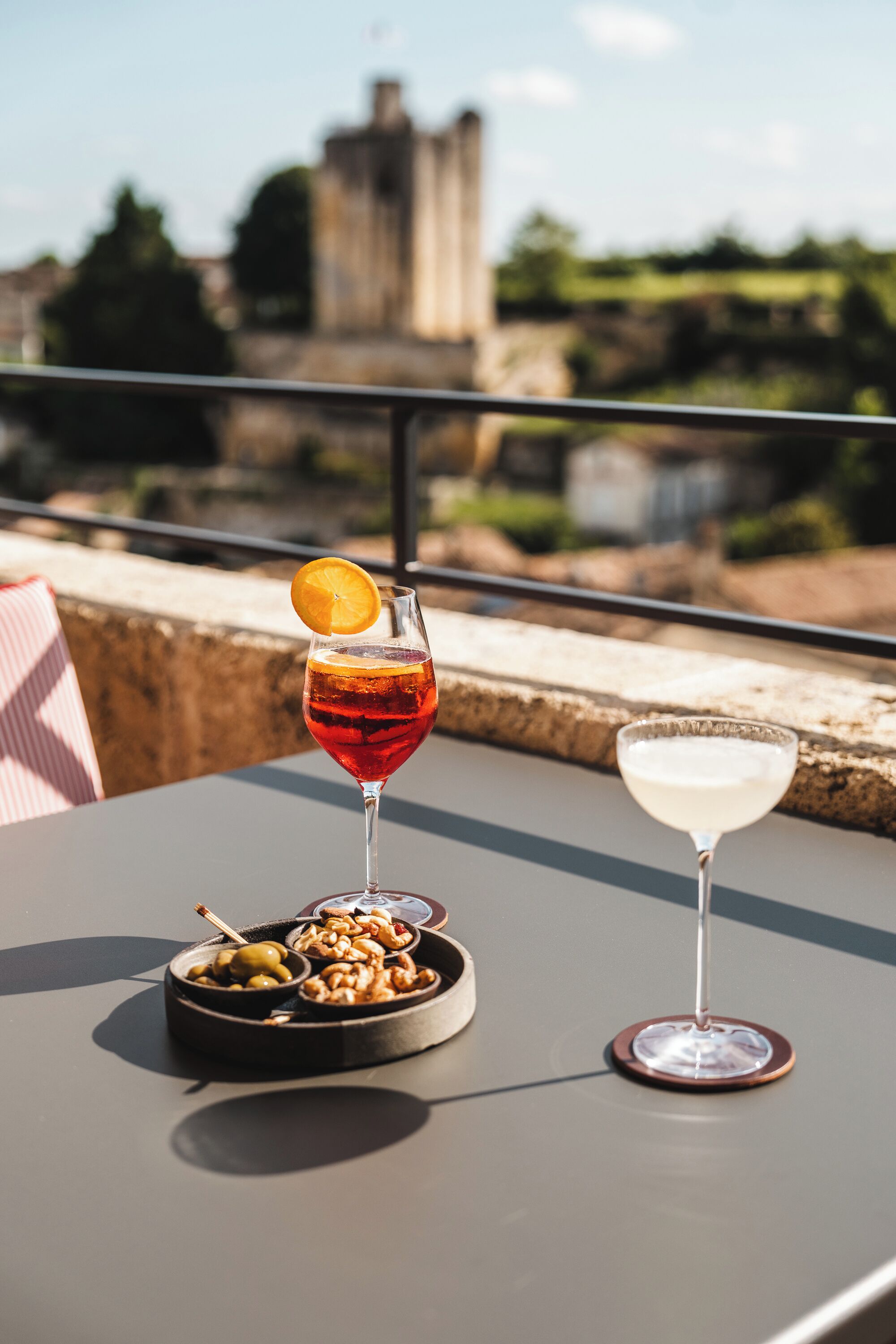 Una mesa con una bebida y un cuenco de nueces, con una vista de un castillo al fondo.