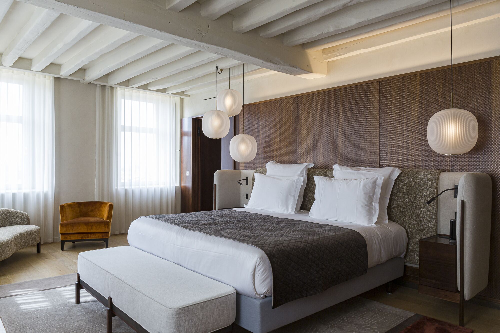A modern bedroom with a large bed, a wooden headboard, and a bench.