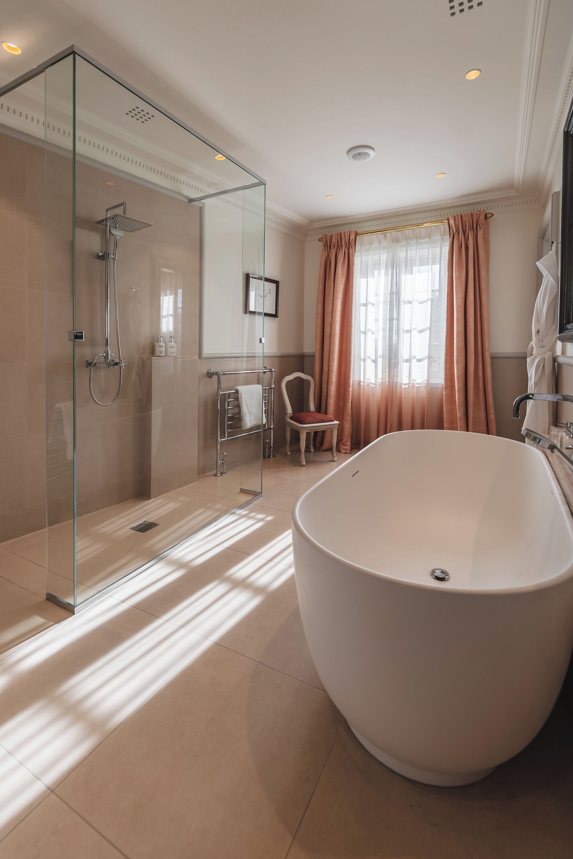A modern bathroom with a glass-enclosed shower, a large freestanding bathtub, and a vanity with a mirror.