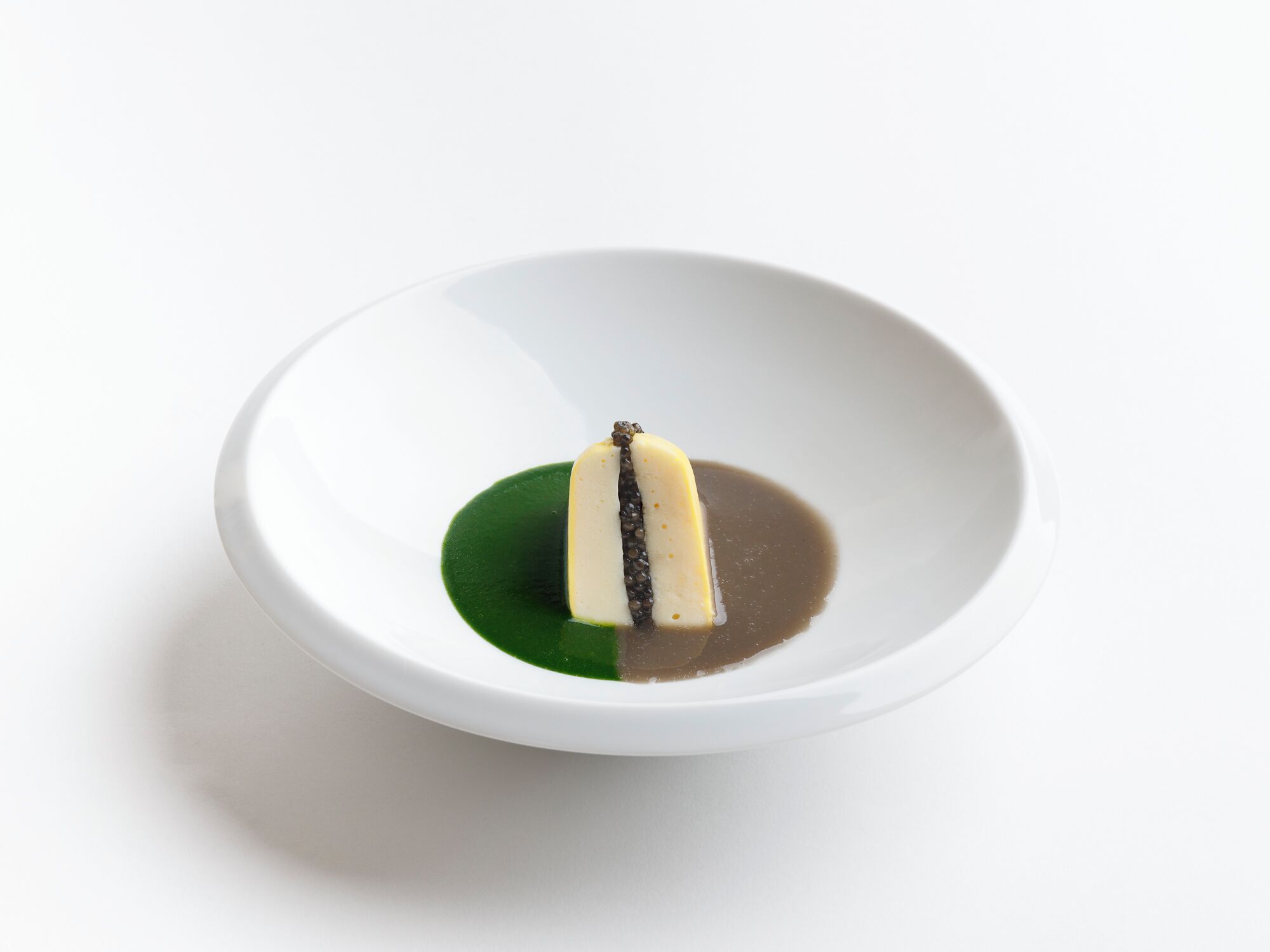 Un plato blanco con un solo bocado de comida, salsa verde y salsa marrón.