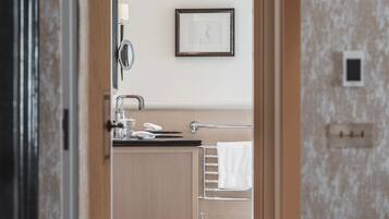 Un baño moderno con tocador de madera, un espejo y un perchero para toallas.