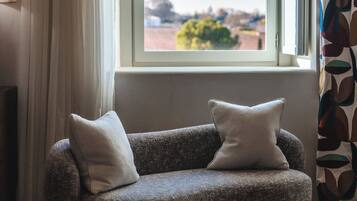 Una sala de estar moderna con un sofá, una ventana que ofrece vistas al exterior y una cortina estampada.