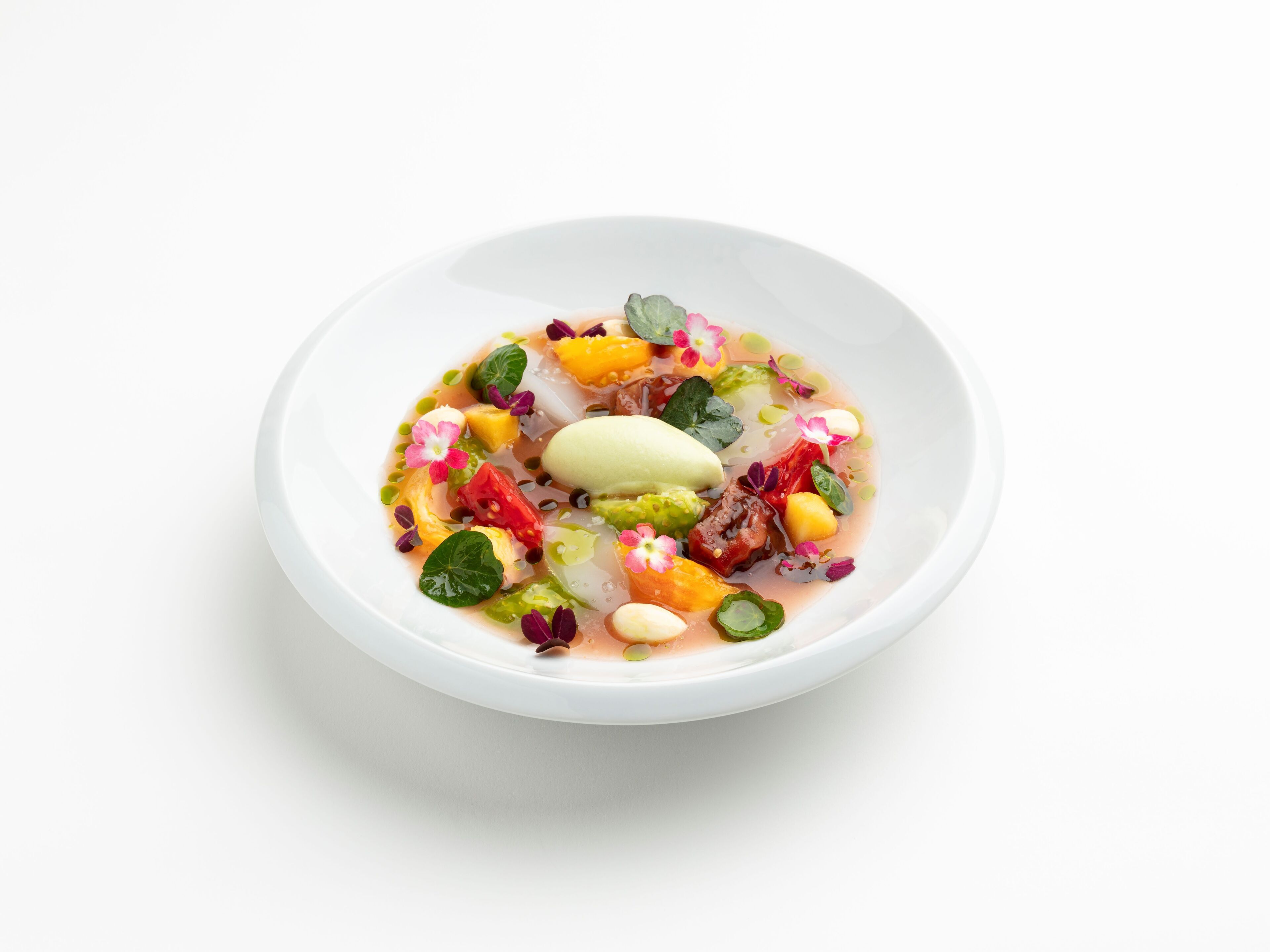 A bowl of colorful dessert with various fruits and flowers.