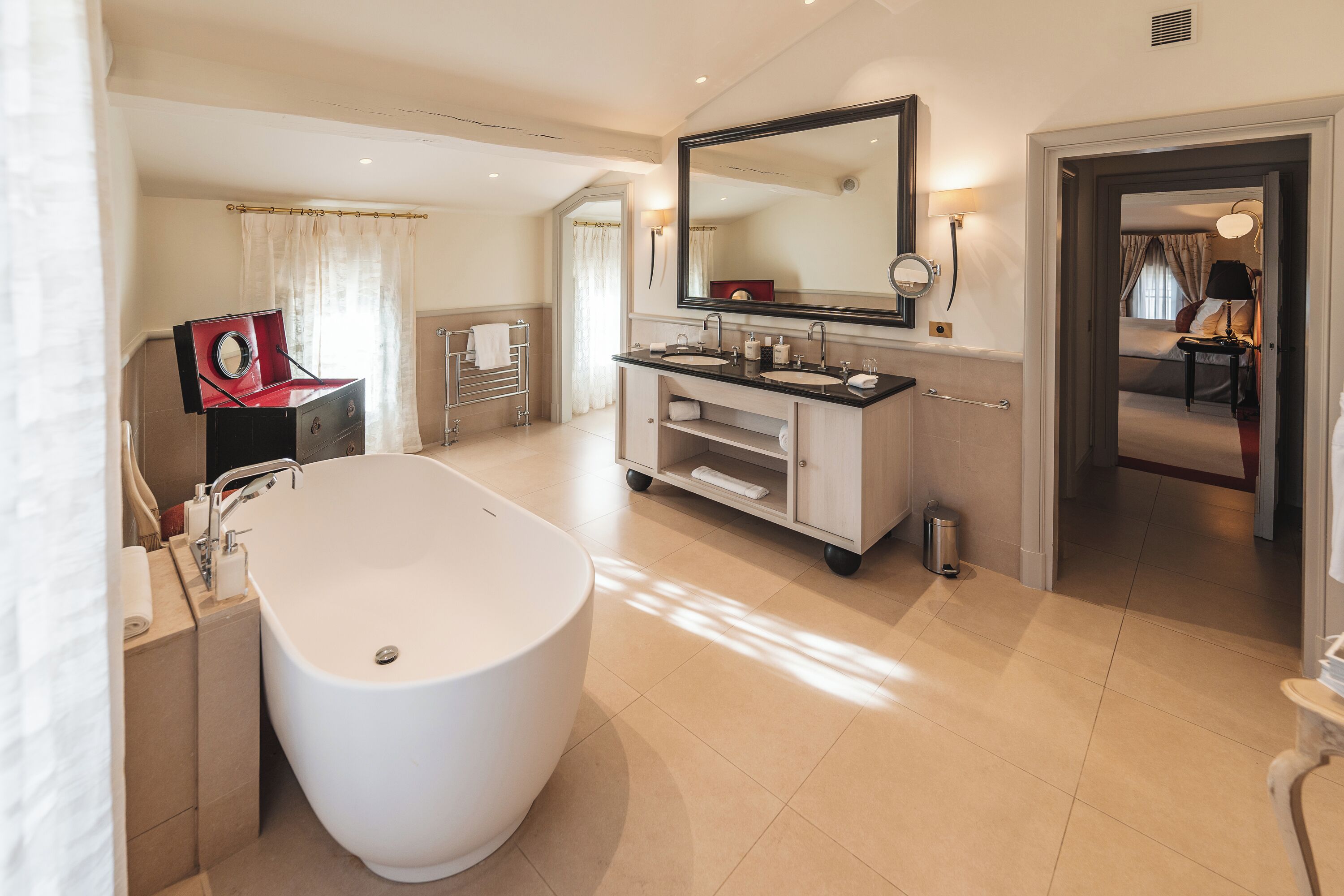 Une salle de bain moderne avec une baignoire sur pieds, un grand miroir et un meuble-lavabo doté de deux vasques.