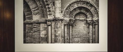 A framed black and white photograph of an arched stone structure on a wall, with a brown leather bench in front.