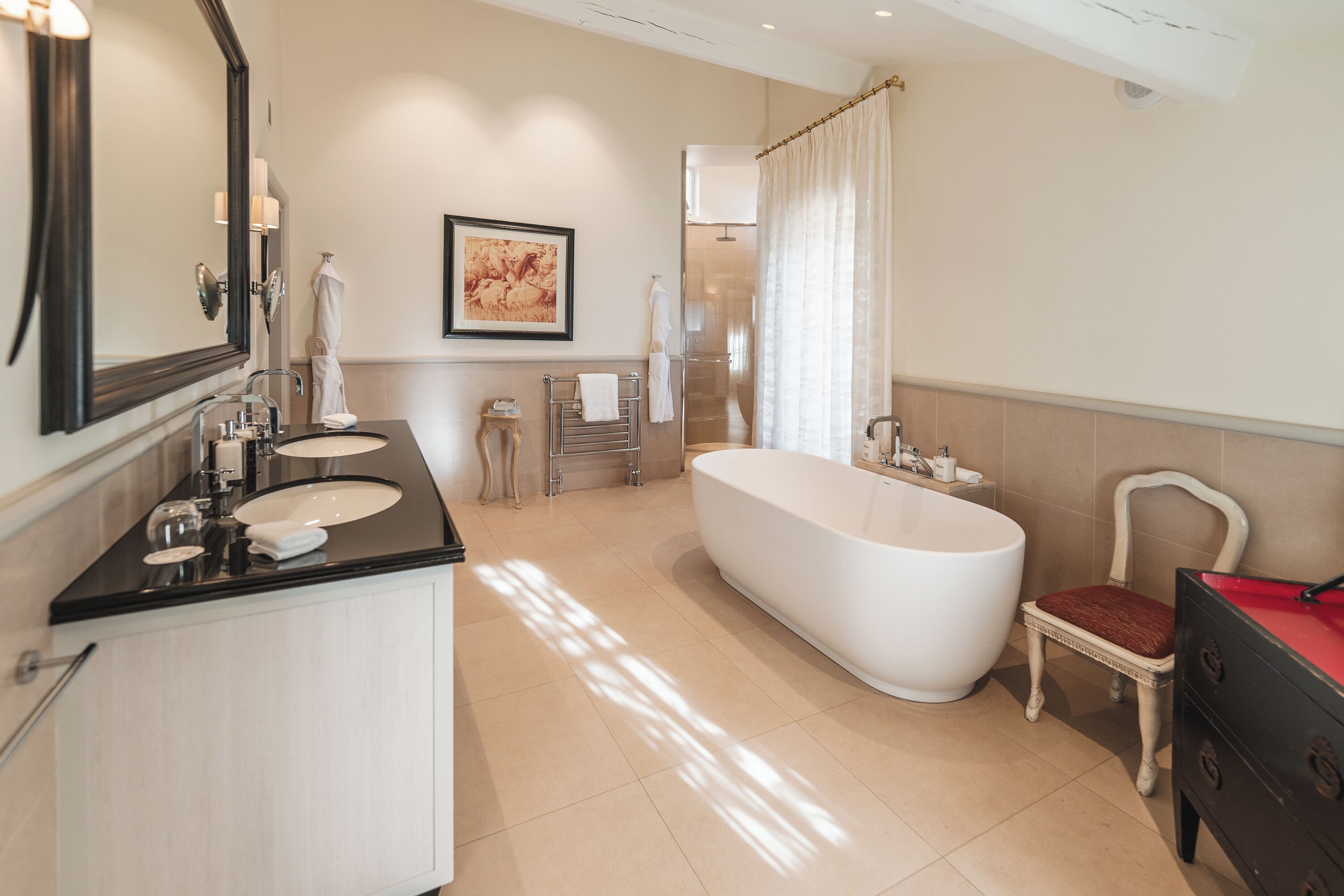 A modern bathroom with a large bathtub, two sinks, a vanity, and a shower area.