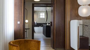 Un salon moderne avec un fauteuil jaune, un plancher en bois et une vue sur la cuisine.