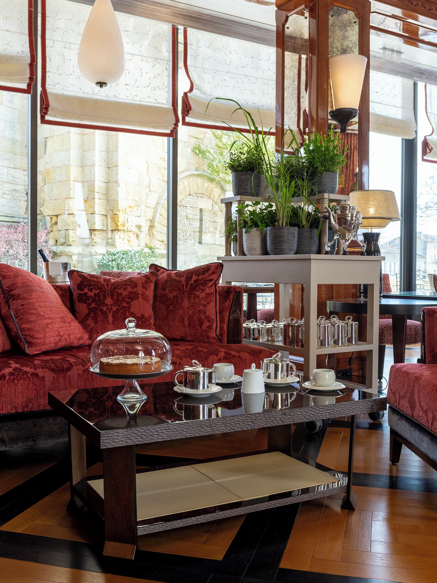 A cozy seating area with a sofa, a coffee table with tea sets, and a plant display.