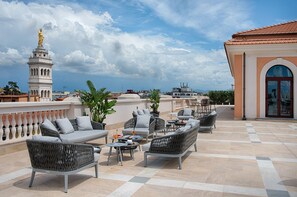 A rooftop terrace with outdoor seating, a statue, and a view of the cityscape.