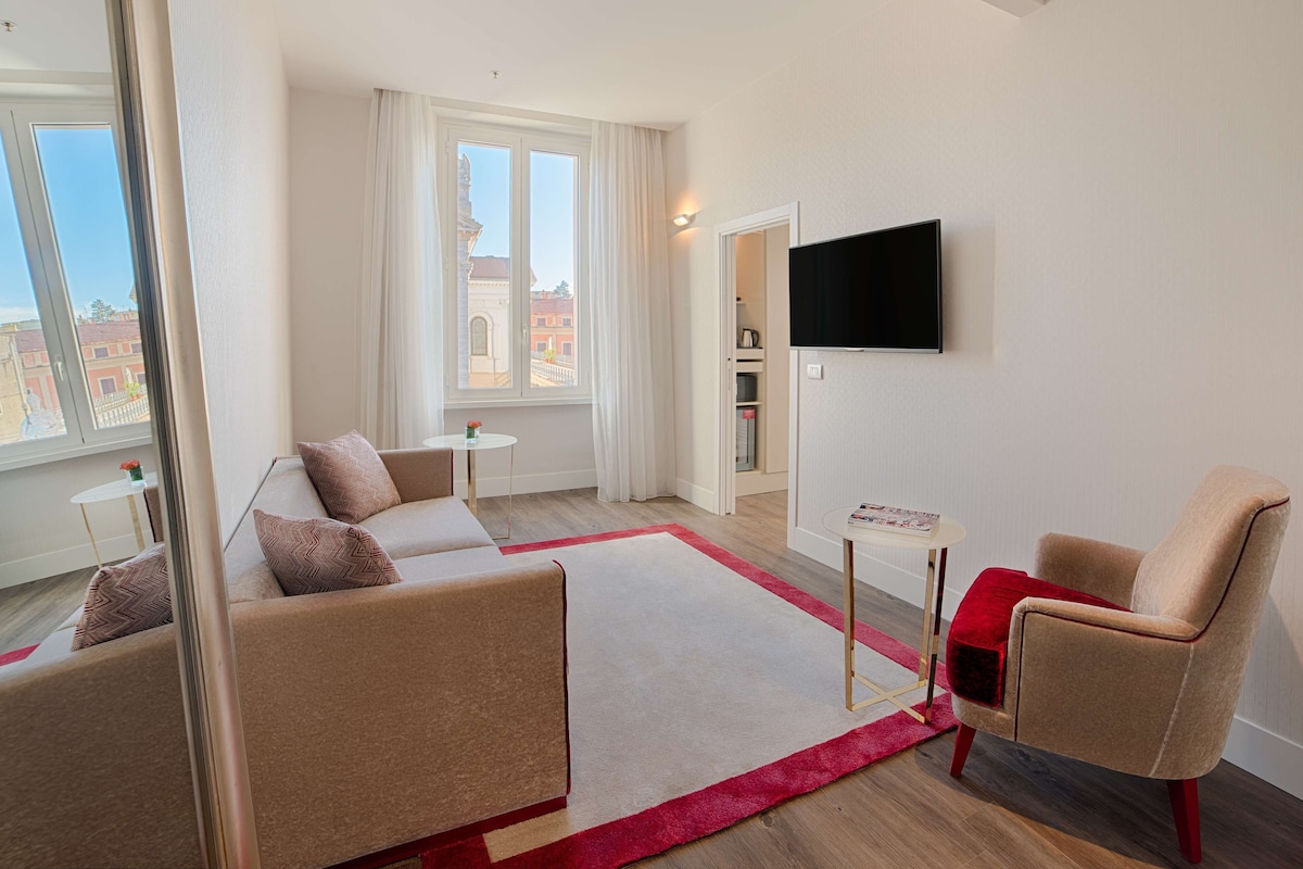 A modern living room with a sofa, armchair, and a flat-screen TV mounted on the wall.