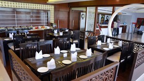 Ein Restaurant mit mehreren Esstischen, gedeckt mit weißen Servietten, Tellern und Besteck.