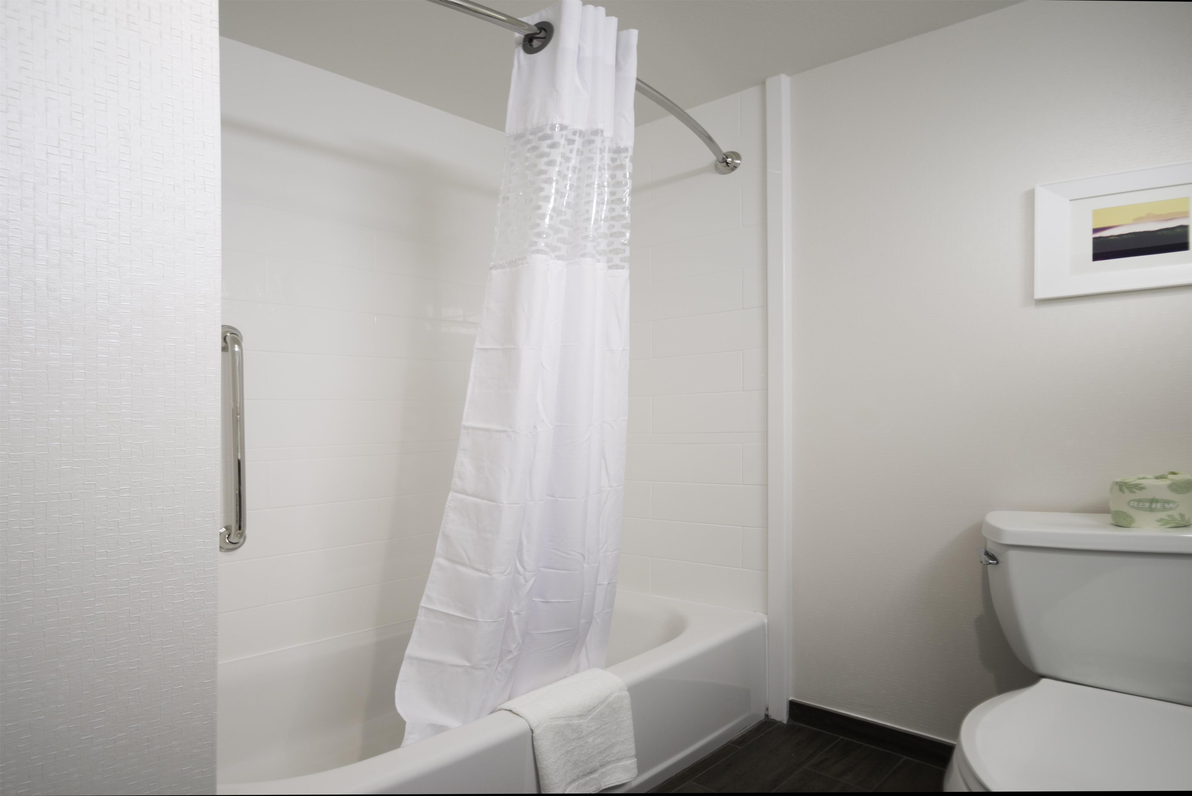 Une salle de bain avec une baignoire blanche, un rideau de douche et des toilettes.