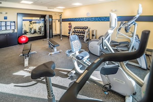 A gym with various exercise equipment including treadmills, a bench, and free weights.