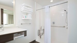 A modern bathroom with a shower, a sink with a mirror, and a towel rack.