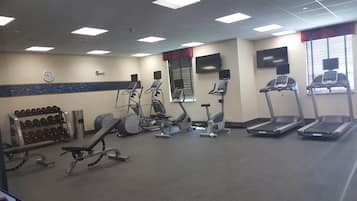 Un gimnasio con cintas de correr, elípticas y pesas libres.
