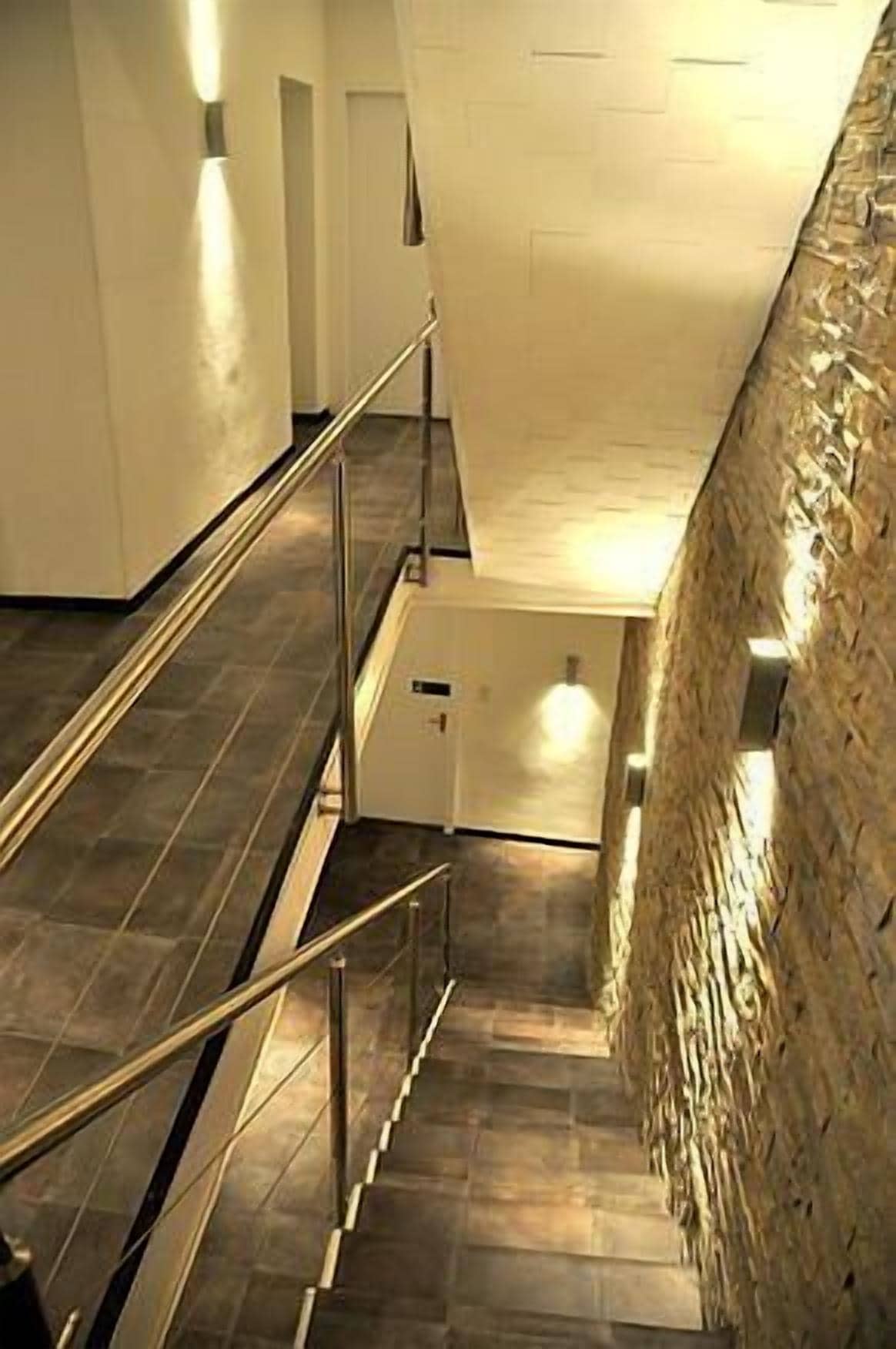 Eine Treppe mit Metallgeländern und einer strukturierten Wand zur Rechten.