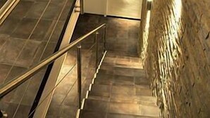 A staircase with metal railings and a textured wall on the right. - Hotel Garni Battello (Melide)