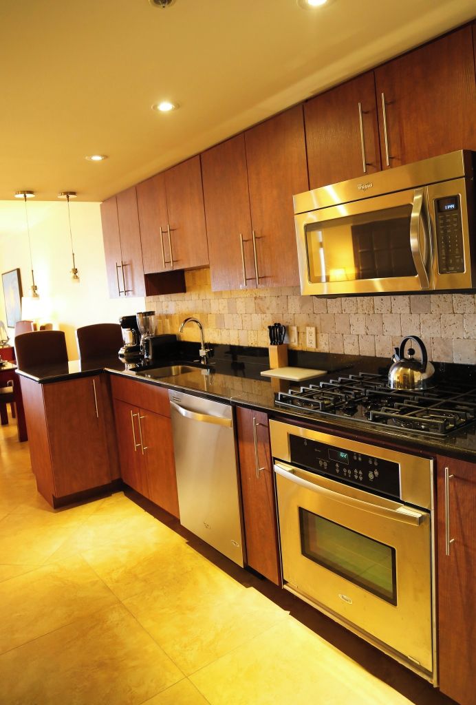 A modern kitchen with stainless steel appliances, wooden cabinets, and a tiled backsplash.