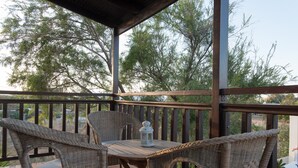 A covered outdoor seating area with wicker furniture and a lantern. - Proimos Maisonnettes (Platanias)