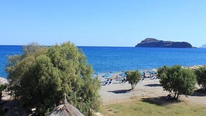 A beach with umbrellas, trees, and a clear view of the sea. - Proimos Maisonnettes (Platanias)