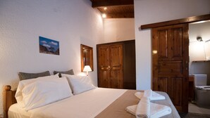 A neatly made bed with white linens, a wooden door, and a small wall-mounted picture. - Proimos Maisonnettes (Platanias)