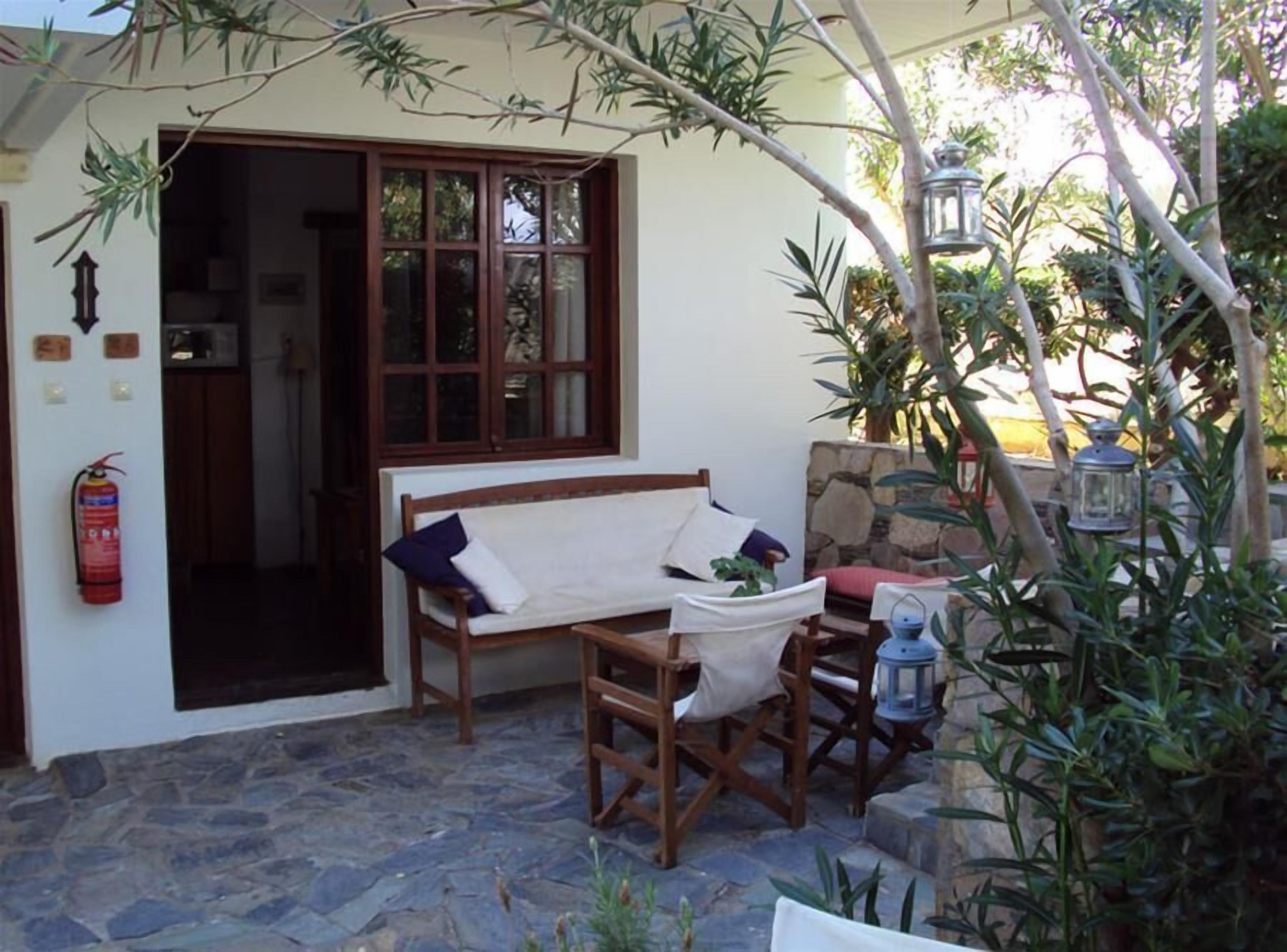 A stone-floored patio with a wooden bench and table, a fire extinguisher, and a lantern.