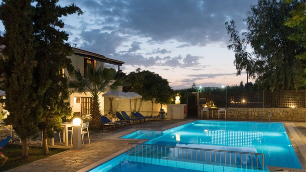 A swimming pool with a stone deck, lounge chairs, and a covered seating area. - Proimos Maisonnettes (Platanias)