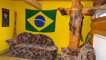 Une pièce comprenant un canapé, une sculpture en bois, un drapeau brésilien et une carte accrochée au mur.