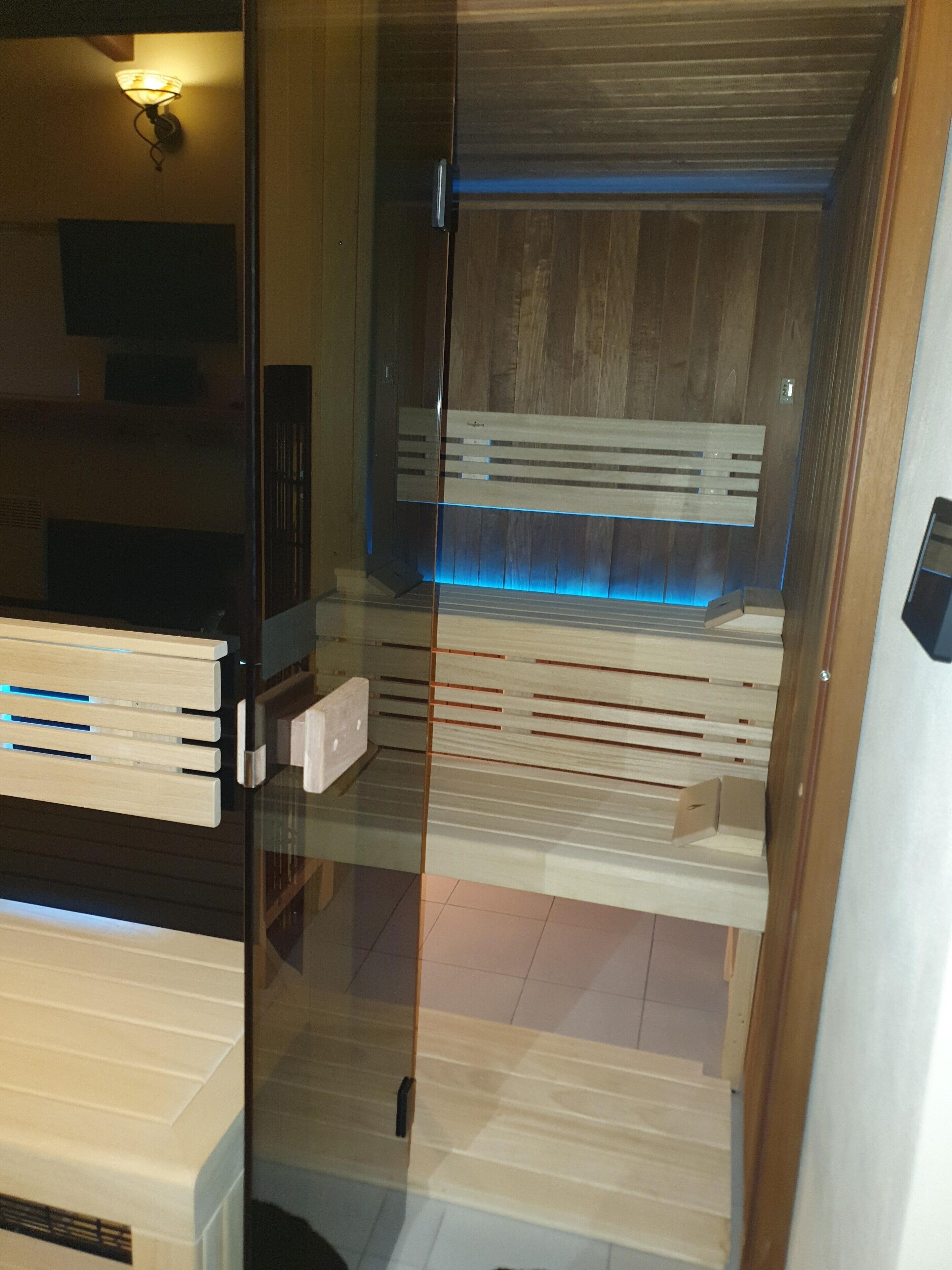 A modern room with a glass partition, wooden paneling, and a bench.
