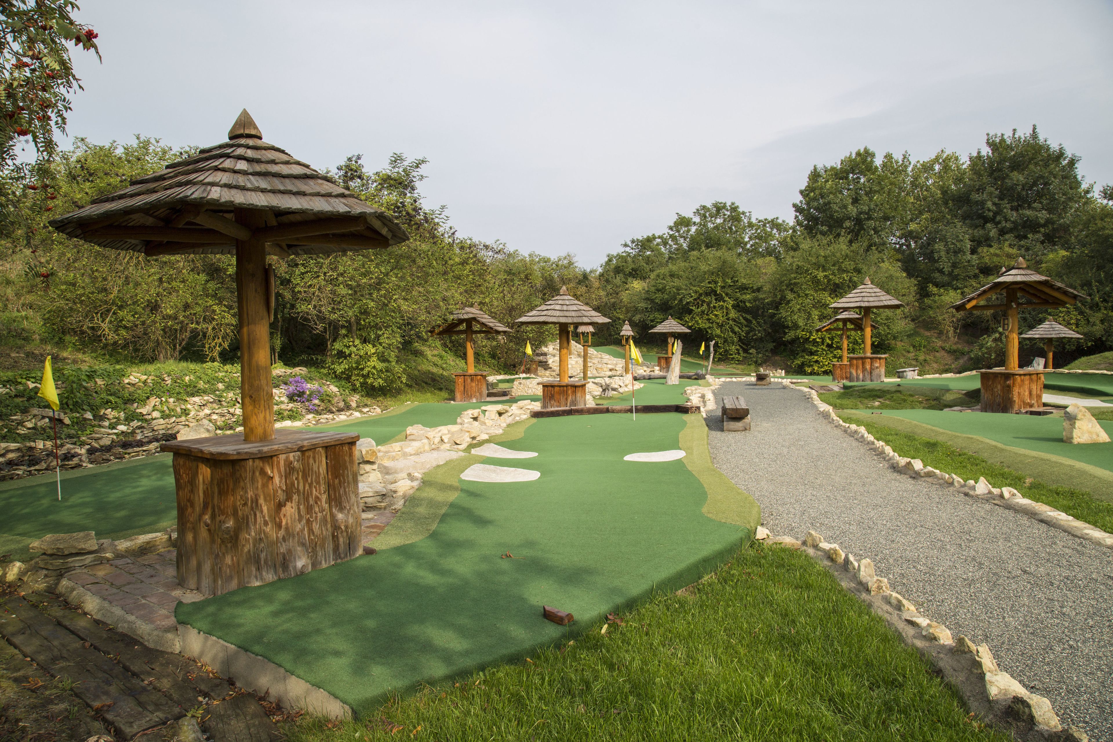 Un campo da golf in miniatura con strutture in legno e un vialetto sterrato.