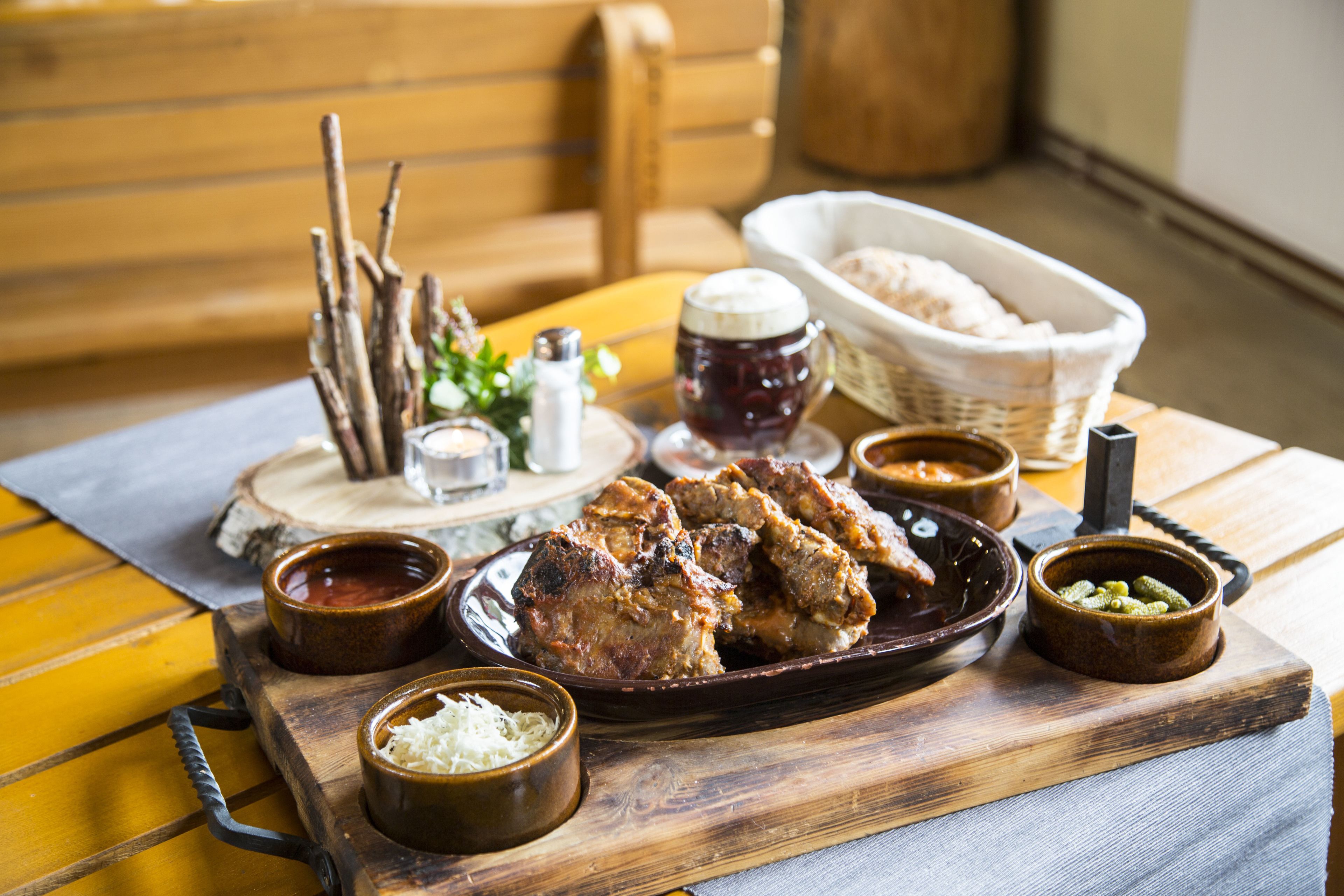 A wooden table with a variety of dishes including meat, bread, and condiments.