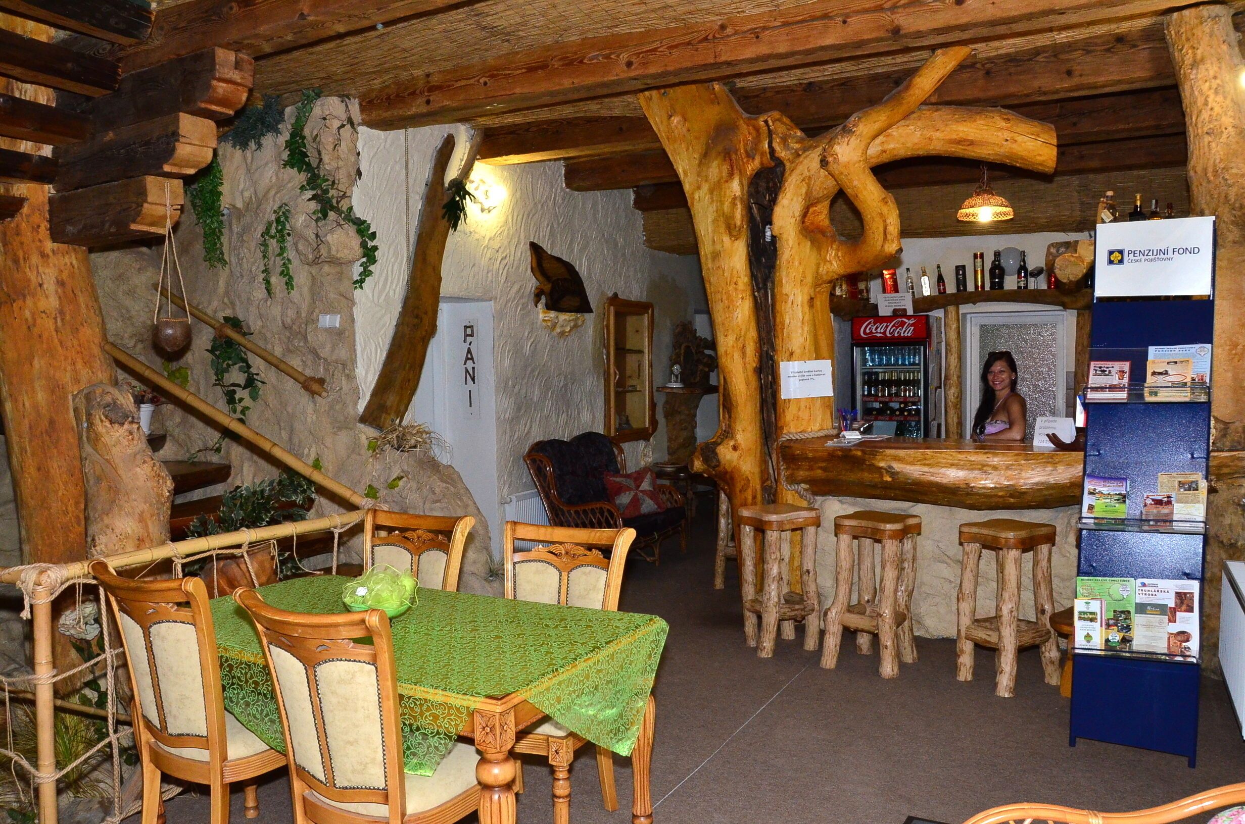 A rustic interior with wooden furniture, a bar area, and a stone wall.