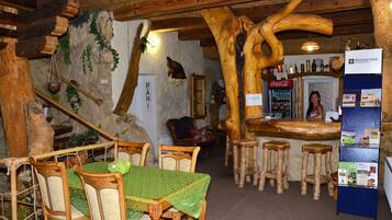A rustic interior with wooden furniture, a bar area, and a stone wall.