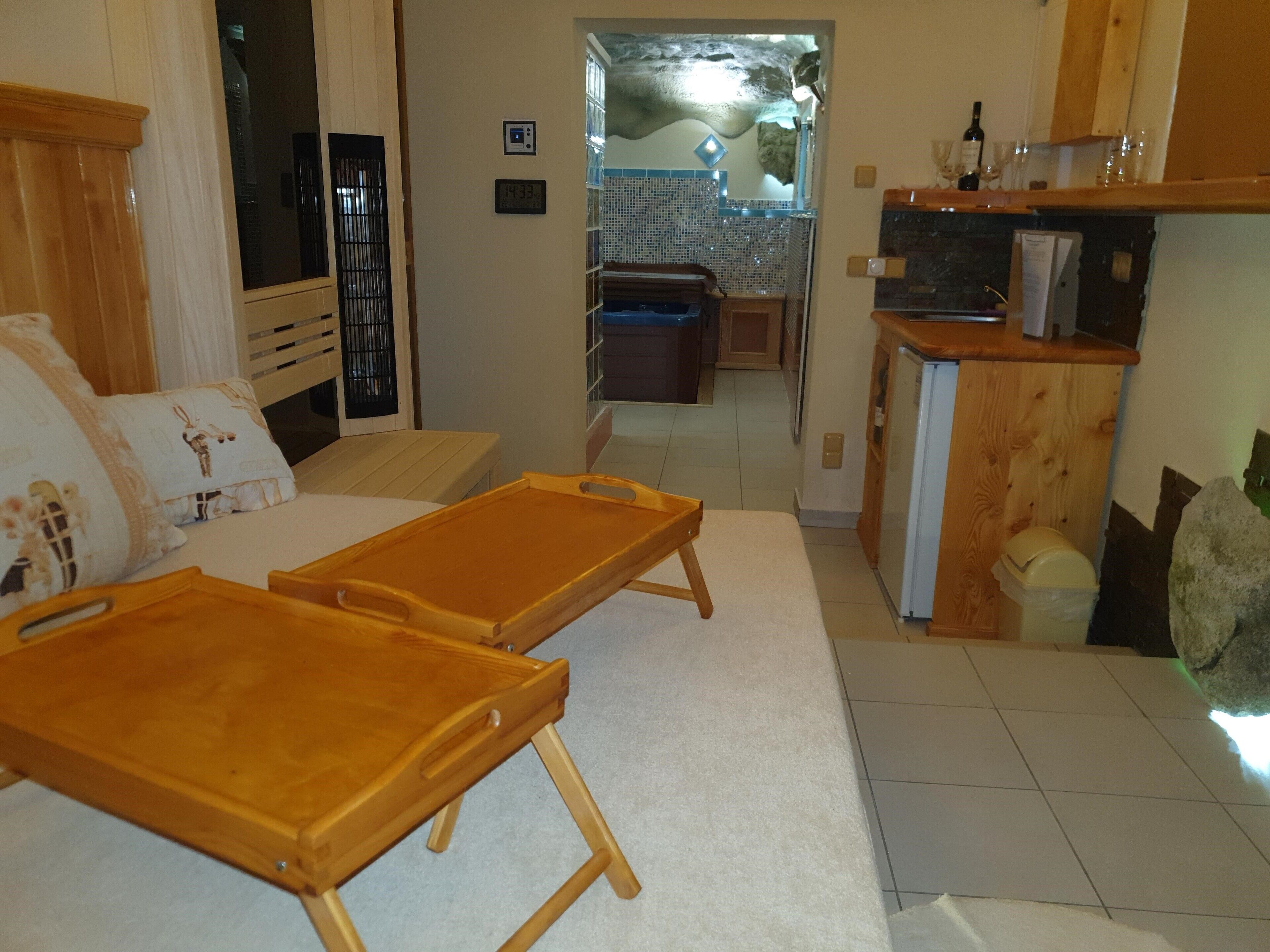 Una habitación con un banco de madera, una cama con almohada de diseño blanco y marrón, un mueble de madera pequeño y un suelo de baldosas.