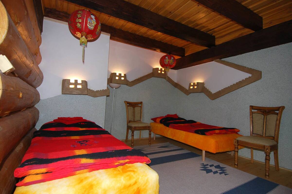 A log cabin-style bedroom with two beds, wooden beams, and decorative wall sconces.