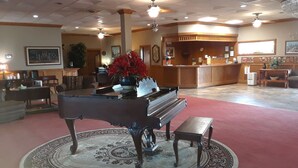 A lobby with a grand piano, a reception desk, and a red carpeted area. - Cedar Glade Resort (Horseshoe Bend)