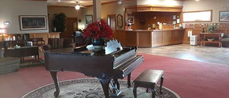 A lobby with a grand piano, a reception desk, and a red carpeted area.