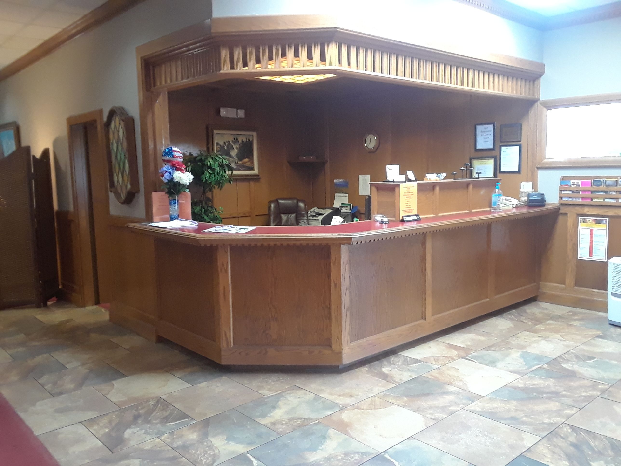 A reception desk with a wooden finish, a clock, and a framed picture on the wall.