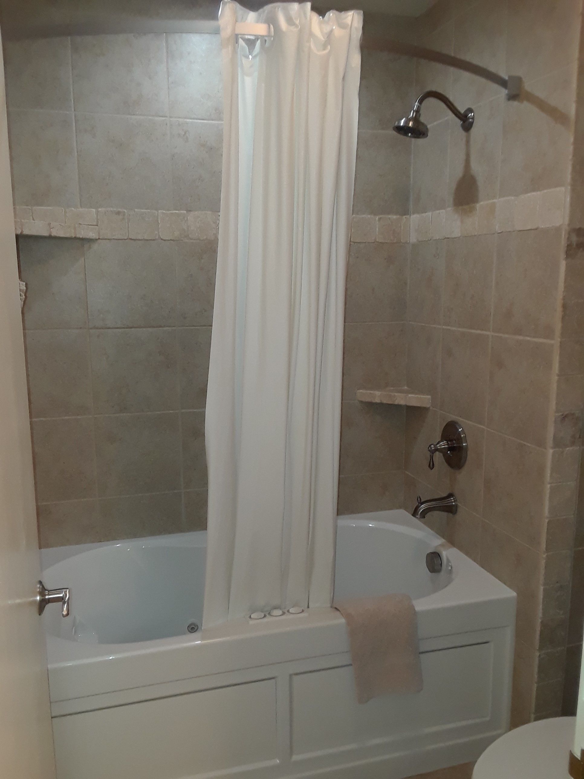 A bathroom with a bathtub, shower, and a towel rack.