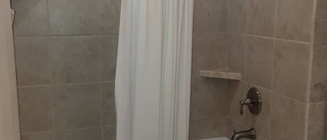A bathroom with a bathtub, shower, and a towel rack.