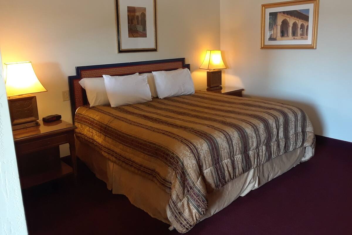 A neatly made bed with a striped bedspread, two bedside lamps, and two framed pictures on the wall.