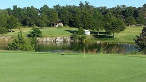 A golf course with a pond, trees, and a sign. - Cedar Glade Resort (Horseshoe Bend)