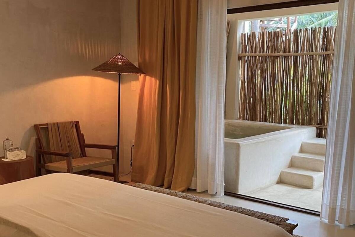 Une chambre d’hôtel avec un grand lit, une chaise, une lampe et une vue sur un balcon avec des marches.
