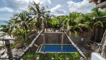 Una piscina rodeada de una cerca de alambrada, con palmeras y un cielo despejado al fondo.