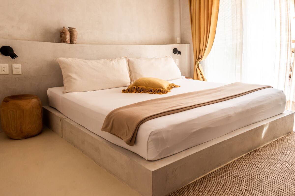 Une chambre moderne avec un grand lit, une table de chevet et une lampe fixée au mur.