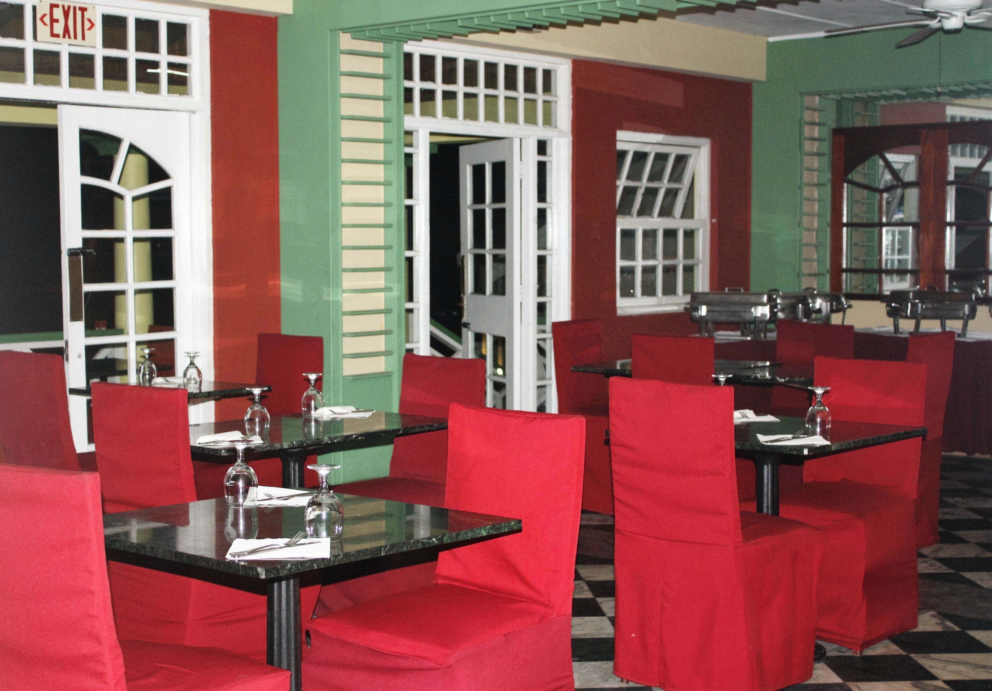 Ein Restaurant mit rot gepolsterten Stühlen und schwarzen Tischen, inklusive eines Fluchtwegschildes und einem Schachbrettmuster auf dem Boden.