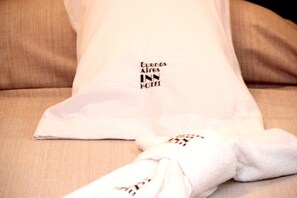 A white pillow with the text "Buenos Aires INN HOTEL" on it, placed on a beige sofa. - Buenos Aires Inn Hotel (Buenos Aires)