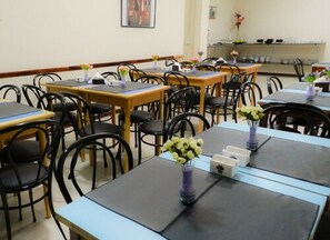 A dining area with tables and chairs, some with flowers. - Buenos Aires Inn Hotel (Buenos Aires)