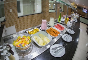 A buffet with various fruits, juices, and breakfast items. - Rede Andrade Araras (Aracaju)